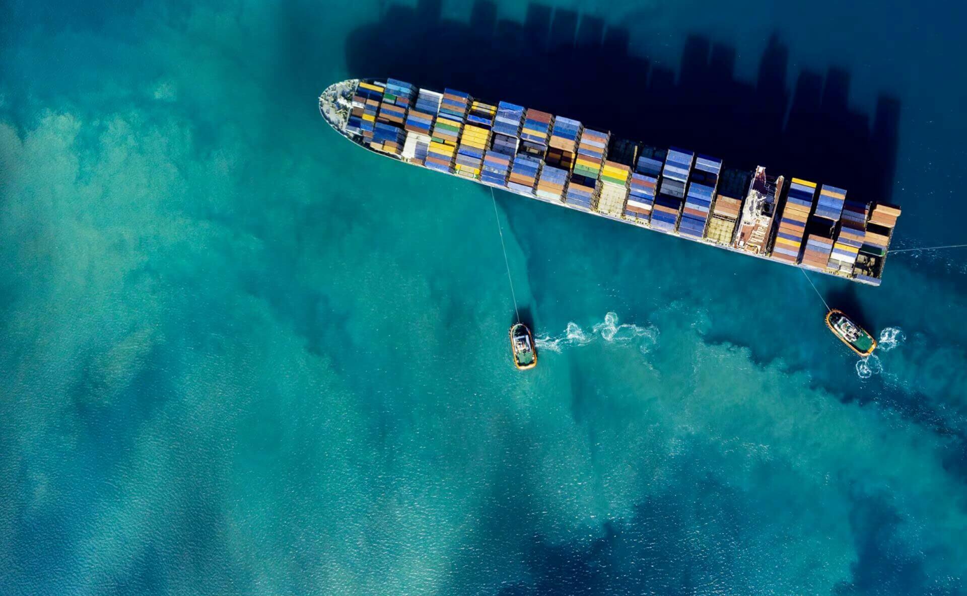 A large shipping boat with smaller boats around it