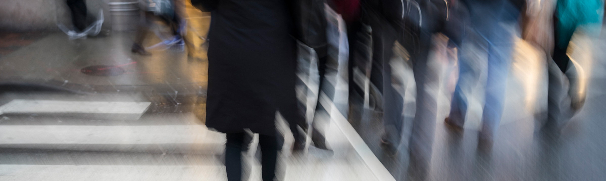 Blurry background of people walking across the street at a crosswalk